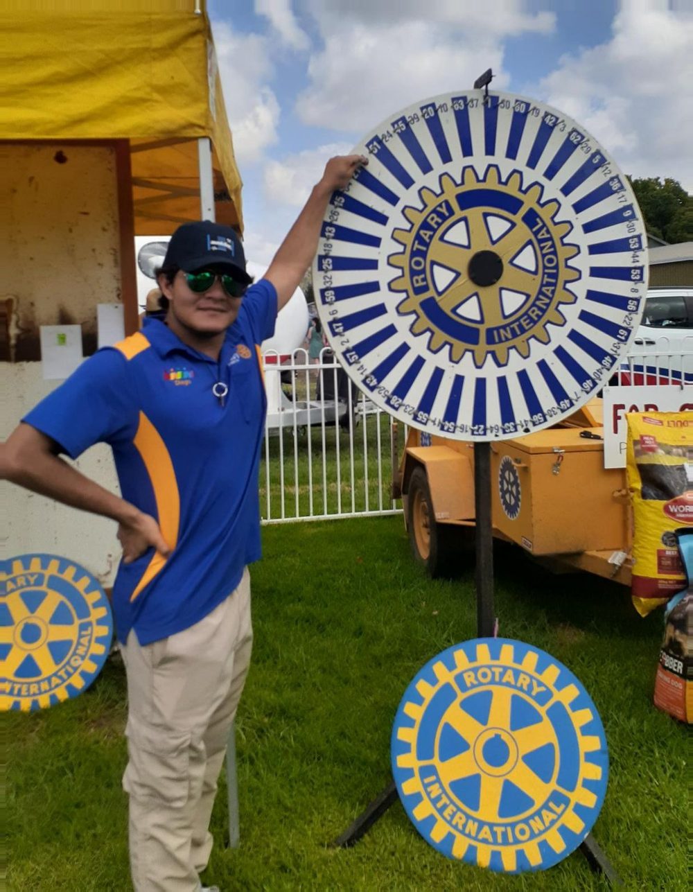 A volunteer beside a large Rotary wheel at a community stall
